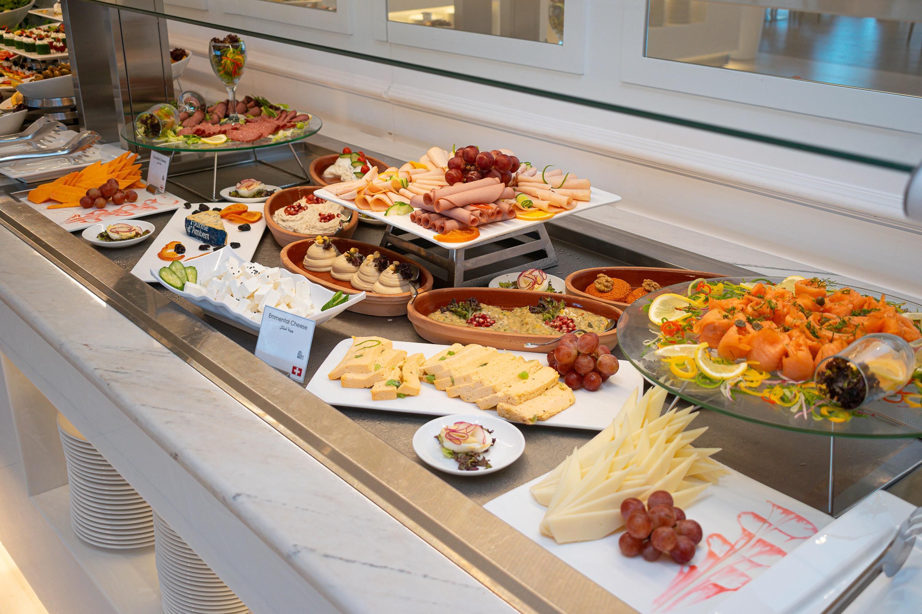 A buffet with various food items including cheeses, meats, and fruits.