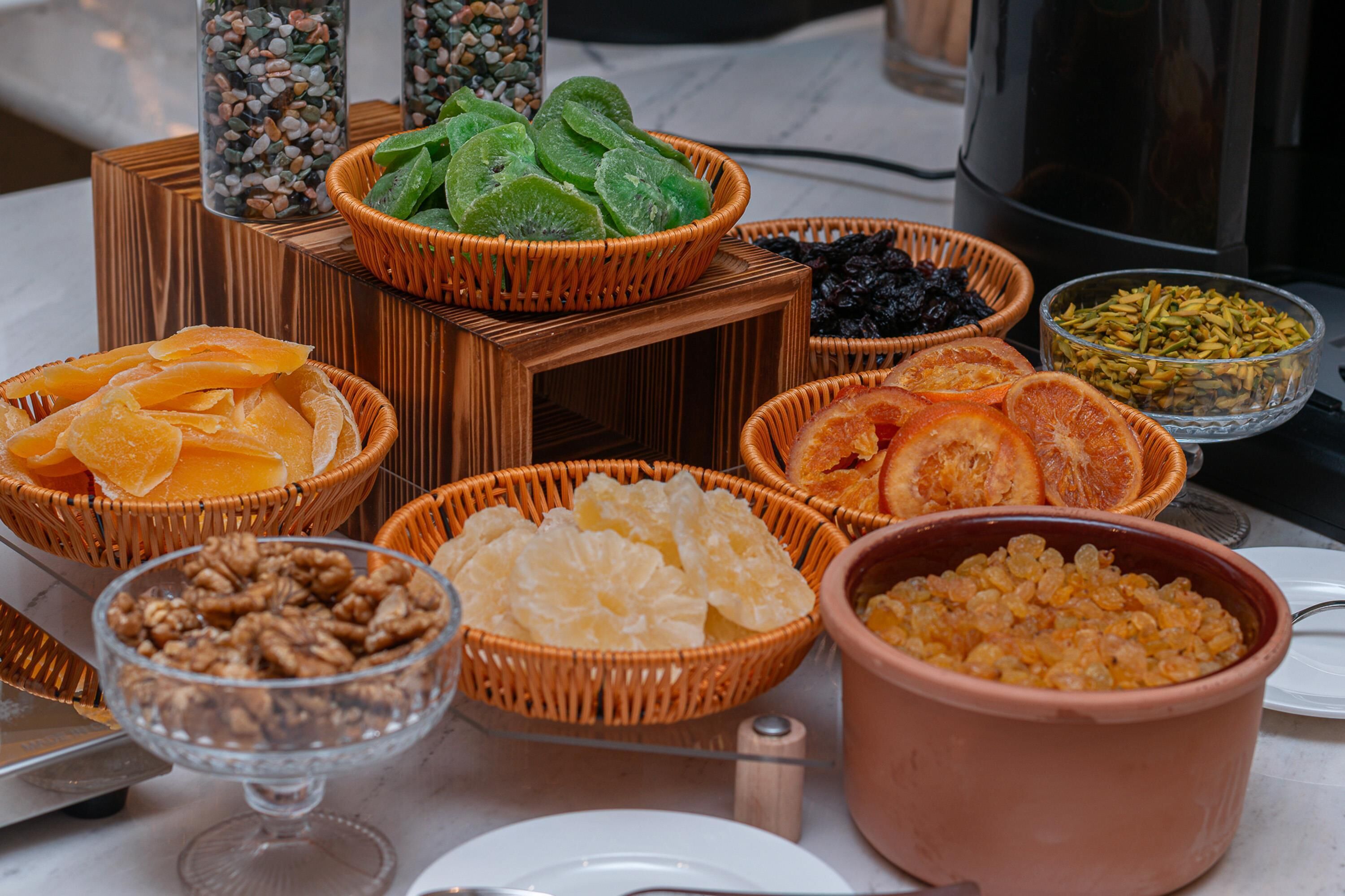 Une table sur laquelle sont disposés divers aliments, notamment des fruits secs, des noix et d’autres en-cas.