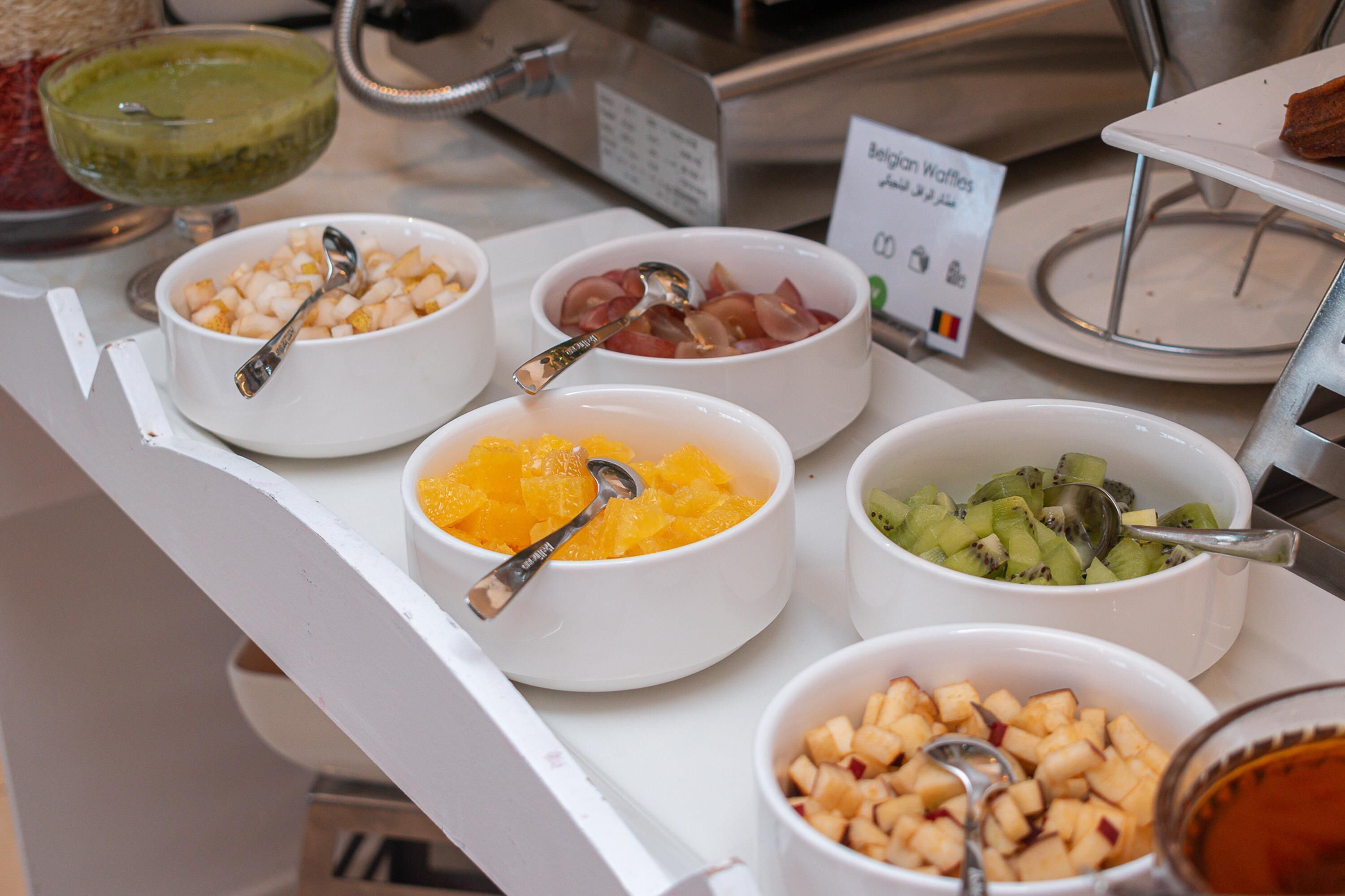 Buffet com diversas opções de frutas e um letreiro indicando waffles belgas.