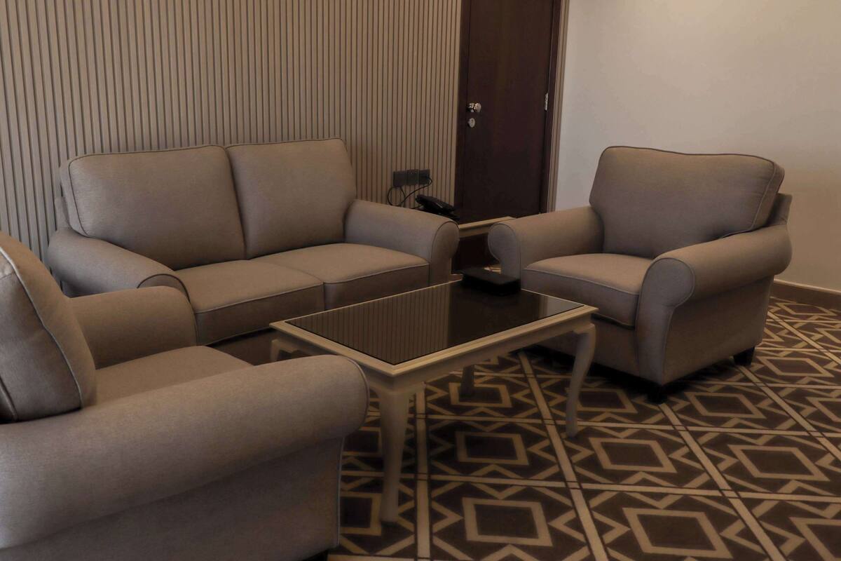 A seating area with a sofa and two armchairs, a small coffee table, and a patterned floor.