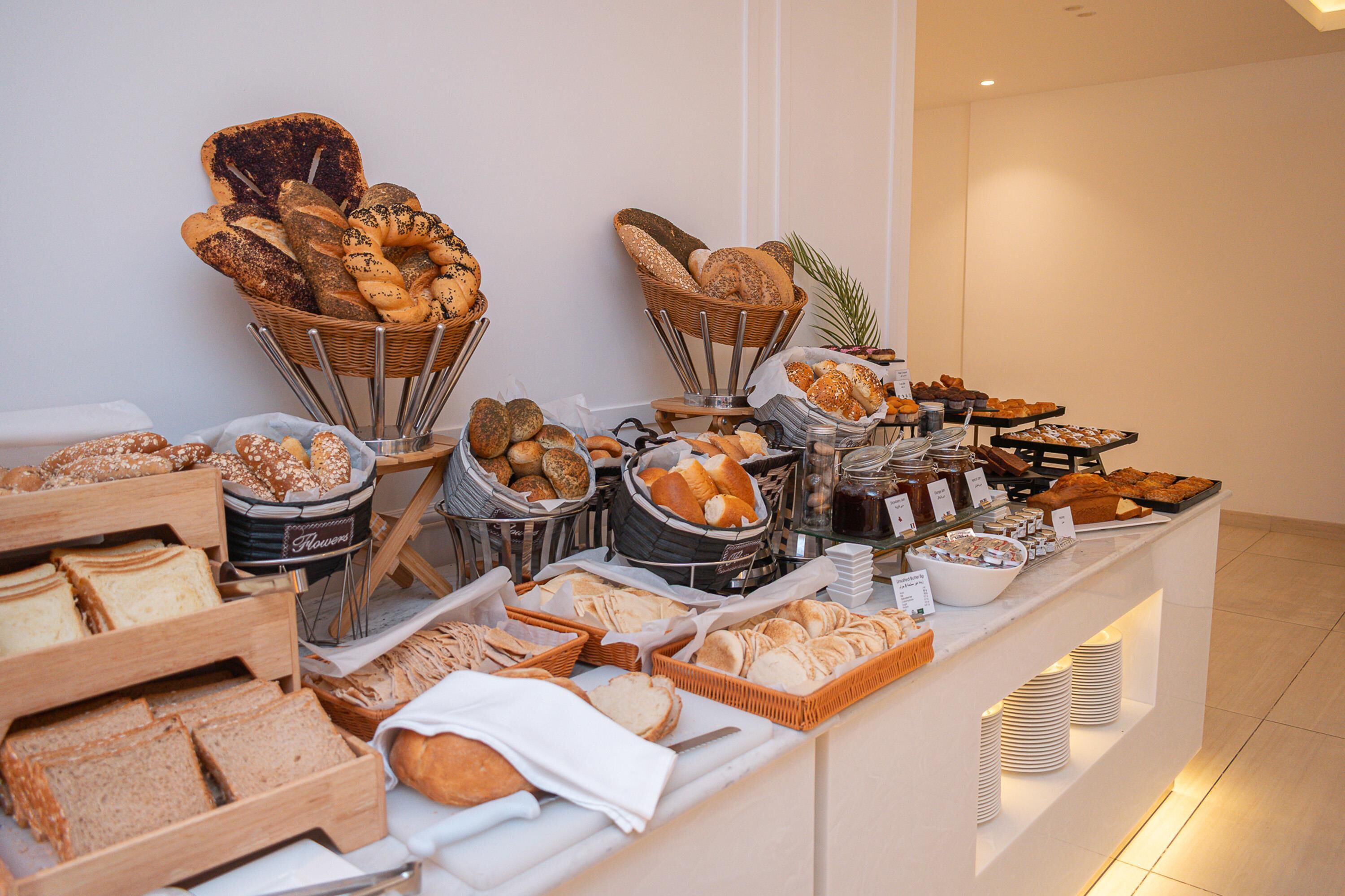 Buffet amb diferents tipus de pa i pastissos exposats en cistells i safates.