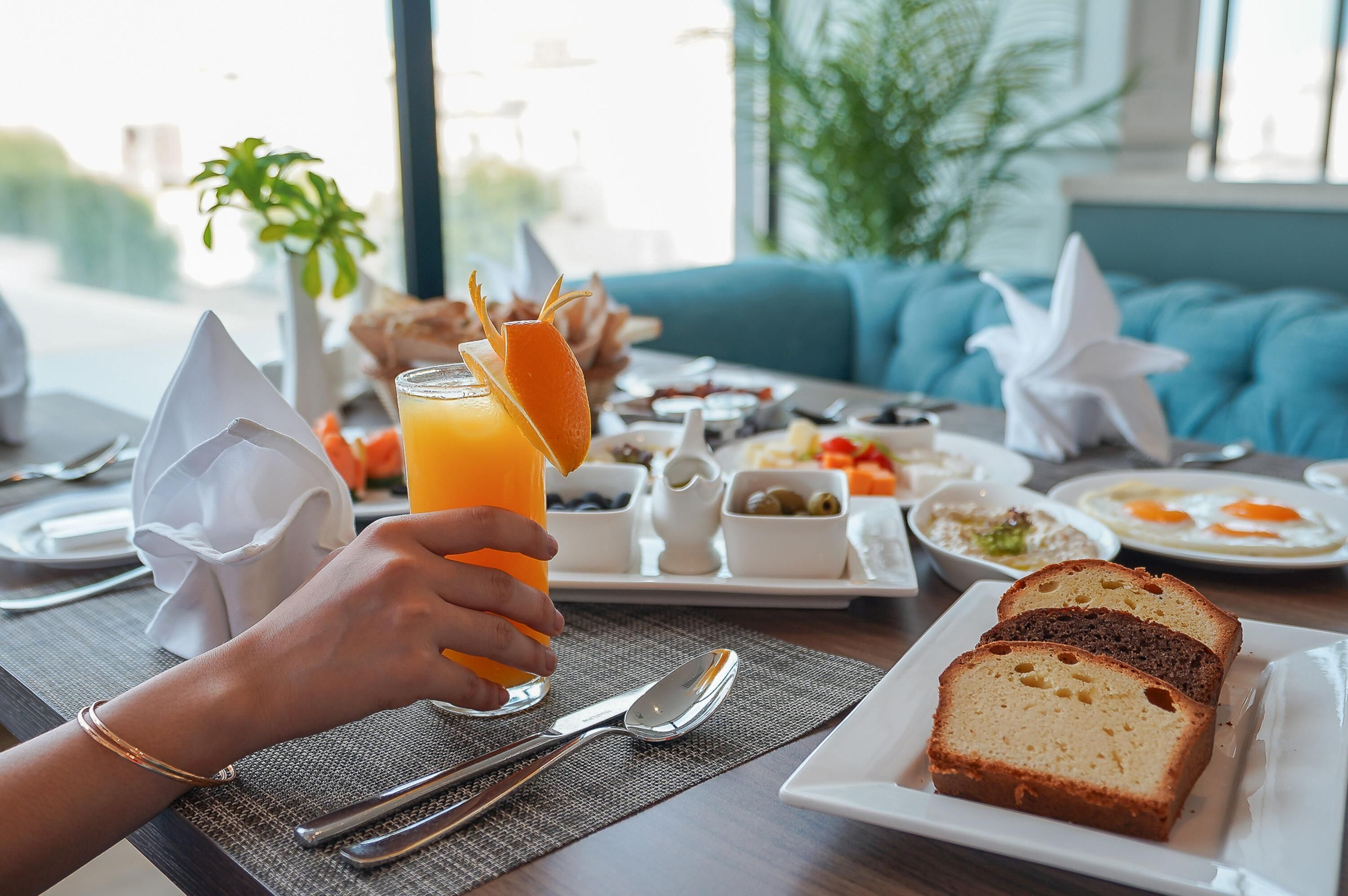 A breakfast setting with a plate of bread, a glass of orange juice, and various side dishes.