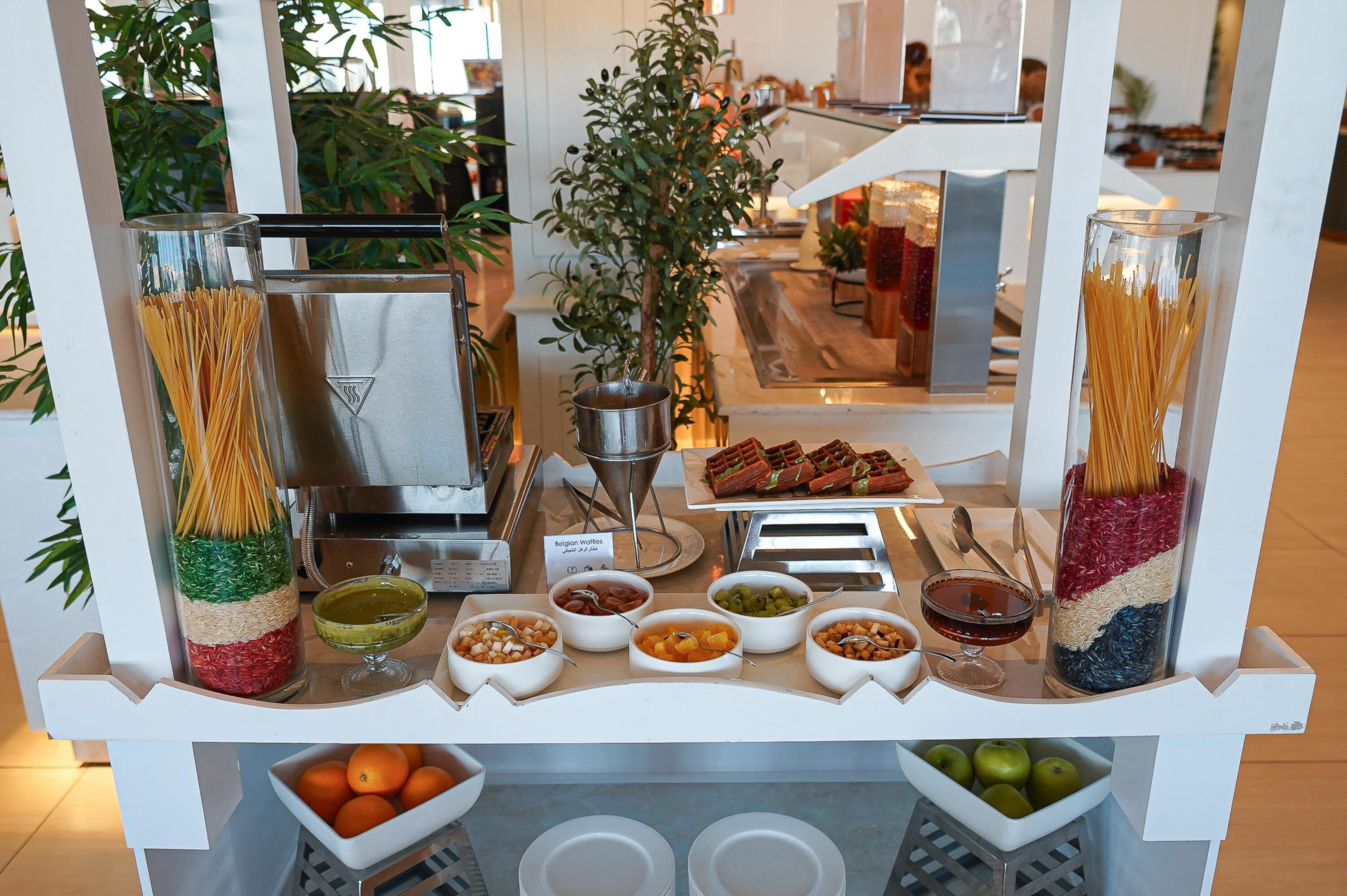 Montaje de bufé con pasta, waffles y diferentes salsas.