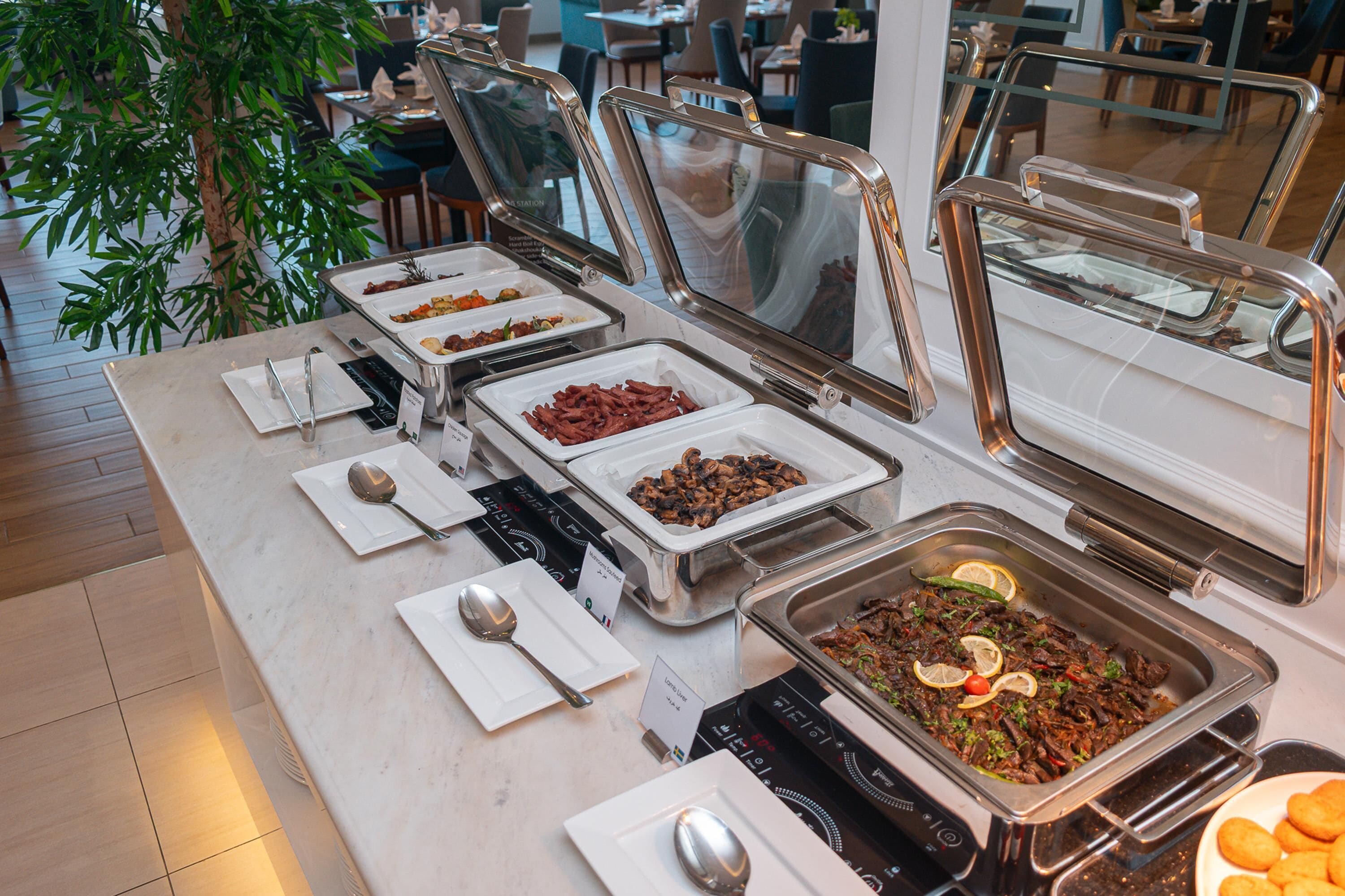 A buffet with various food options, including meats and salads, in a well-lit indoor setting.