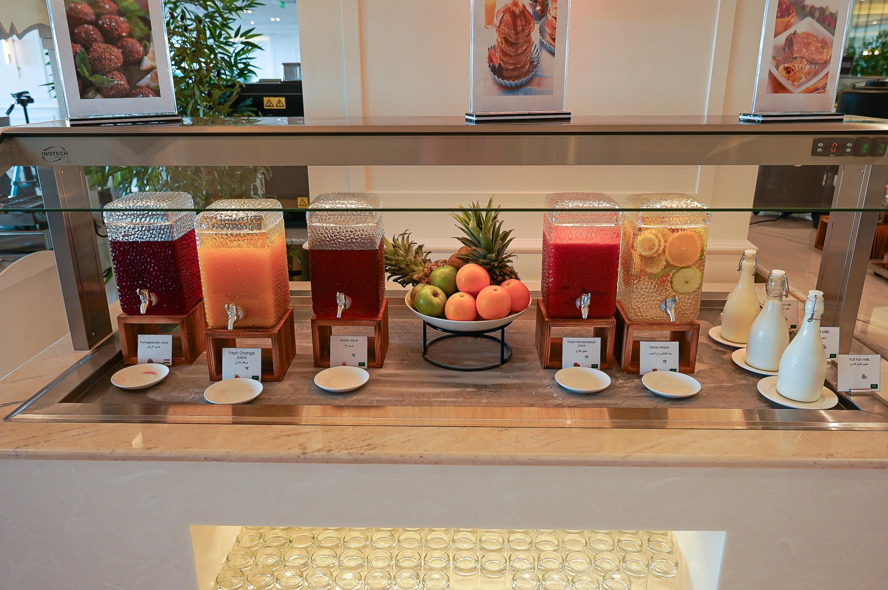 A juice bar with various fruit juices and a selection of fruits on display.