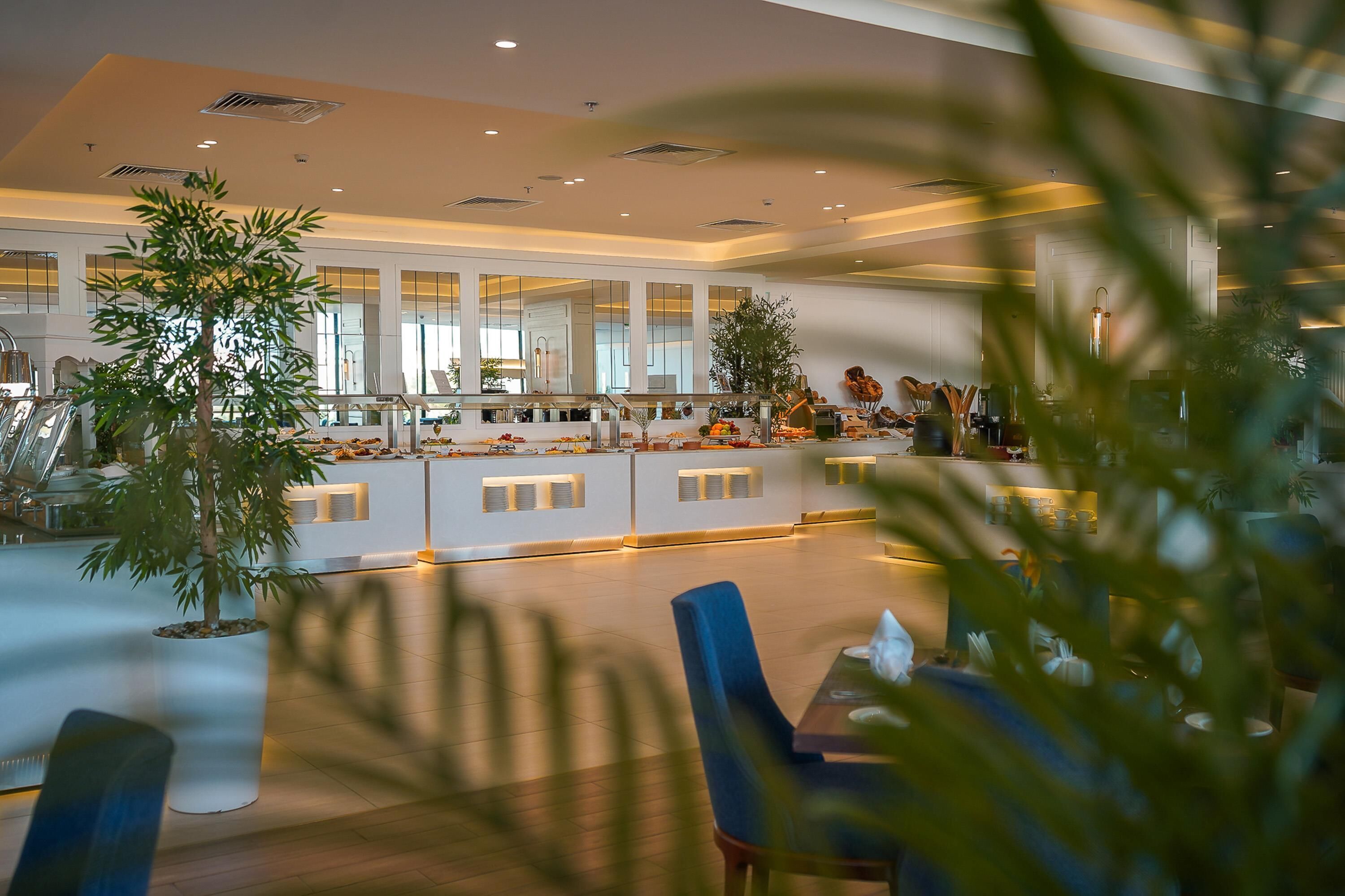 A spacious hotel lobby with a central counter, seating area, and large windows.