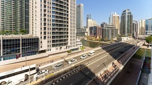 A modern urban skyline with high-rise buildings, a river, and a multi-lane highway. - Your gateway in Sparkle Tower JBR by Suiteable (Dubai)