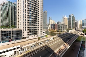A modern urban skyline with high-rise buildings, a river, and a multi-lane highway.