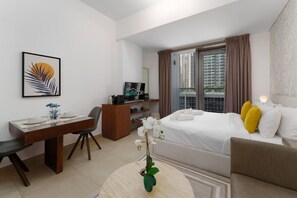 Una habitación de hotel con cama, escritorio, silla, televisor y ventana con cortinas.