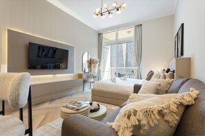 A modern living room with a flat-screen TV, sofa, armchair, and a coffee table.