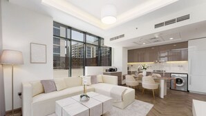 A modern living room with a sofa, coffee table, and dining area. - Chic 1BR Apartment in Azizi Riviera, Meydan (Dubai)