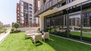 A modern building with a rooftop garden, outdoor seating, and large windows. - Chic 1BR Apartment in Azizi Riviera, Meydan (Dubai)