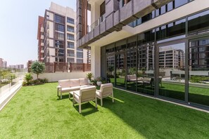 A modern building with a rooftop garden, outdoor seating, and large windows.