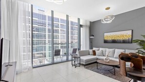 A modern living room with a large window, a sofa, a coffee table, and a TV.