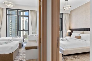 A hotel room with a large window, a bed, a seating area, and a nightstand with a lamp.