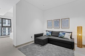 A modern living room with a grey sectional sofa, a grey rug, and three framed artworks on the wall. - Stunnigly furnished and spacious apartment in JVC (Dubai)