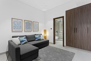 Ein modernes Wohnzimmer mit einem grauen Sofa, einem Holzschrank und gerahmten Kunstwerken an der Wand.
