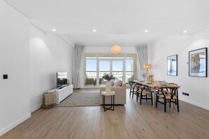 A modern living room with a sofa, TV, dining table, and chairs.