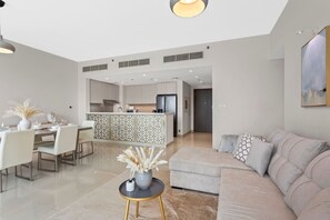 Un salon moderne comprenant un canapé, une table à manger et des chaises. Il y a également un coin cuisine avec des placards et un réfrigérateur.