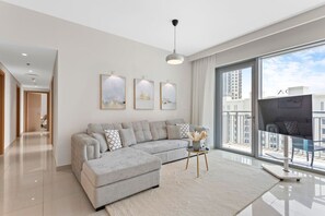 A modern living room with a grey sectional sofa, a glass coffee table, and abstract wall art. - Luxurious Living 3 Bedroom at Harbour Views (Dubai)