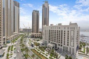 A modern urban area with high-rise buildings, a central plaza with palm trees, and a waterfront view.
