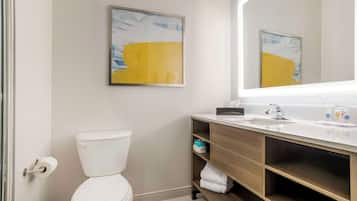A modern bathroom with a toilet, a sink, and a mirror. There are two framed artworks on the wall.