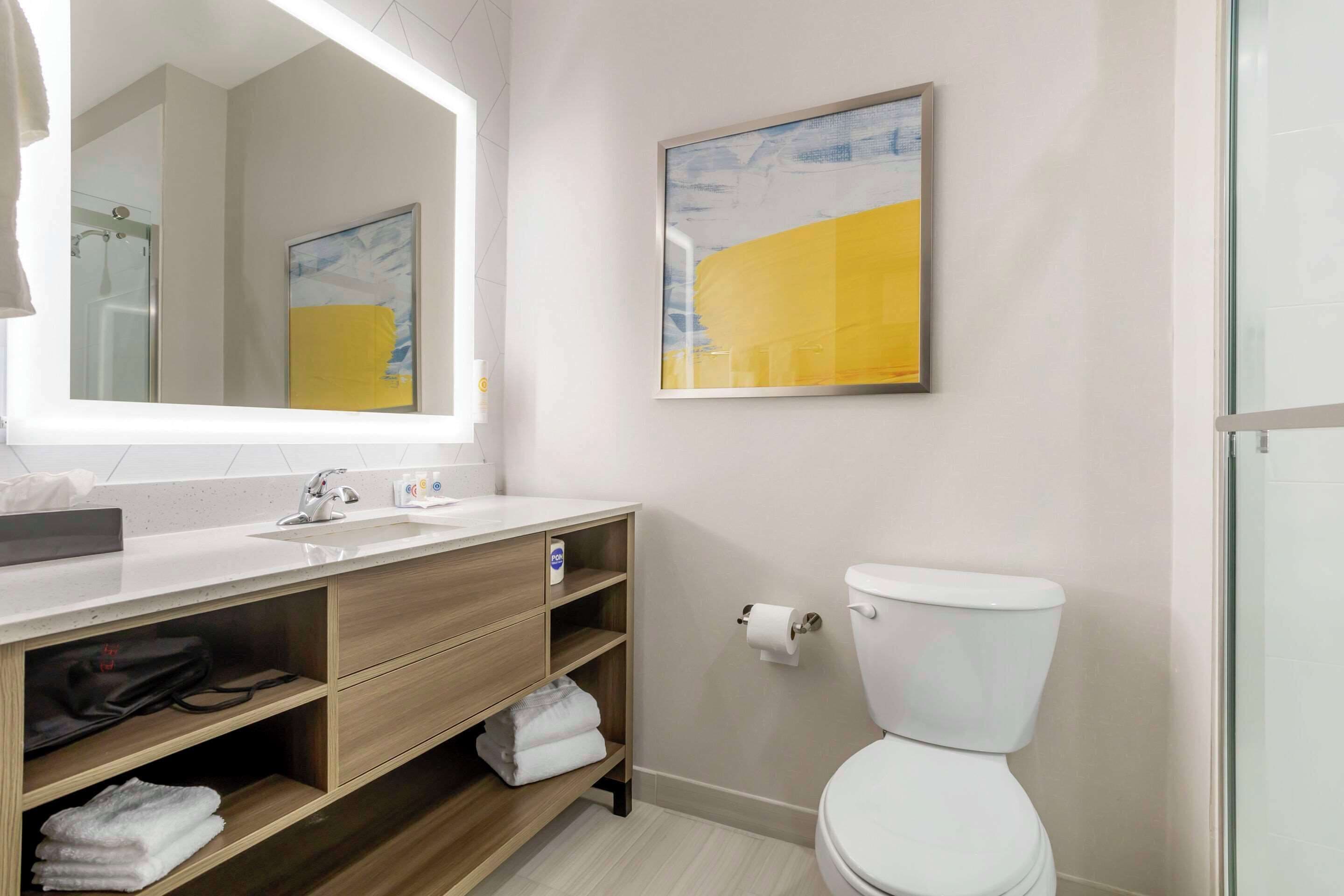 A modern bathroom with a white sink, wooden vanity, and a toilet.