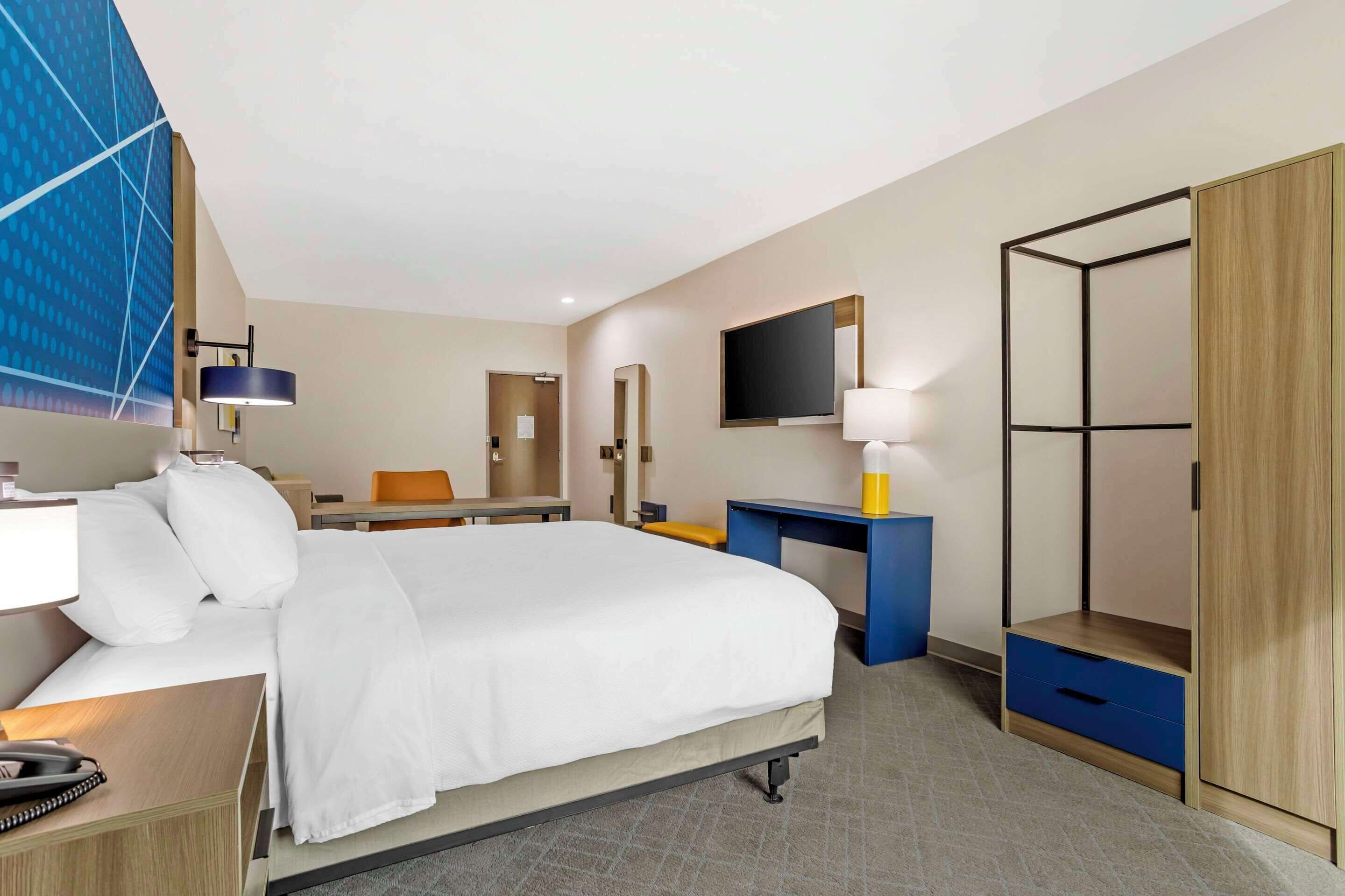 Een hotelkamer met een groot bed, een bureau, een kledingkast en een televisie.