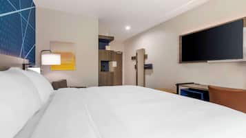 Une chambre d’hôtel avec un grand lit, un bureau, un téléviseur à écran plat et un téléviseur fixé au mur.