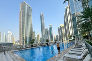 Une piscine avec des chaises longues et une vue sur la ville en arrière-plan.