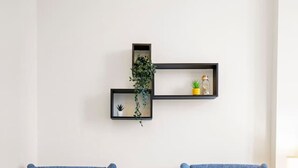 Ein Zimmer mit zwei blauen Sesseln mit gelben Kissen, einem kleinen runden Tisch und einem gewebten Teppich.