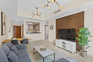 A modern living room with a sofa, dining table, TV, and a potted plant.