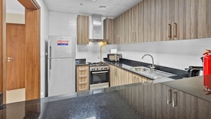Eine moderne Küche mit eingebautem Herd, Backofen und einer Mikrowelle, Holzschränken und einem Edelstahl-Kühlschrank.