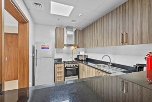 A modern kitchen with a built-in stove, oven, and microwave, wooden cabinets, and a stainless steel refrigerator.