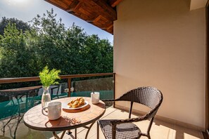 A round table with a plate of croissants, a white mug, and a vase with a plant on a balcony with a view of trees. - Apartment '4 Terraza - Antilles Sin Jardin' with Mountain View and Private Terrace (Llanes)