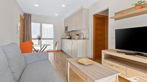 A modern living room with a sofa, dining table, and TV stand.
