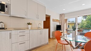 A modern kitchen with a microwave, cabinets, and a dining area with orange chairs and a glass table.