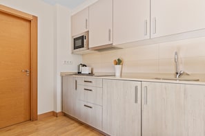 A modern kitchen with wooden cabinets, a microwave, a sink, and a coffee maker.