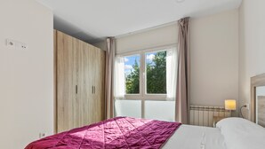 Ein Schlafzimmer mit Bett, Fenster, Heizkörper und Kleiderschrank.