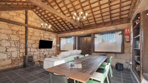 A rustic room with a stone wall, wooden beams, a fireplace, a sofa, a dining table with chairs, and a television. - Vacation Apartment 'Tosca' with Sea View, Shared Pool and Wi-Fi (Las Vegas)