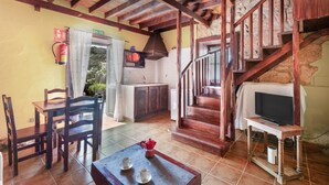 A rustic interior with a wooden staircase, a dining area with chairs and a table, a kitchen with a stove, and a television on a stand. - Vacation Apartment 'Tosca' with Sea View, Shared Pool and Wi-Fi (Las Vegas)