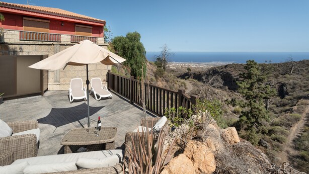 A terrace with wicker furniture, a table with a bottle and glass, and a view of the sea. - Vacation Apartment 'Tosca' with Sea View, Shared Pool and Wi-Fi (Las Vegas)