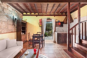 A cozy living area with a sofa, dining table, chairs, and a kitchen area with a staircase.