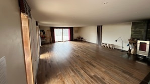 A spacious room with wooden flooring, a large window, and a fireplace.