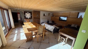 Un interior de madera con una mesa de comedor, sillas, un sofá y un televisor.