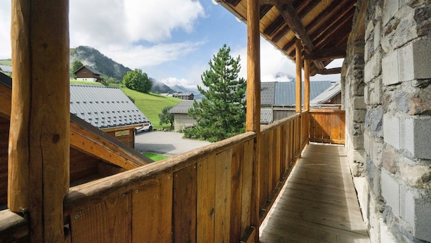 A wooden balcony with a view of a mountain and a house.