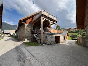 Un refugio rústico de montaña con balcón de madera, paredes de piedra y un cartel que dice 'Le Ferme du Solail'.