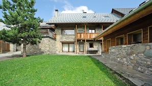 A two-story stone building with a stone facade, wooden balconies, and a well-maintained lawn.