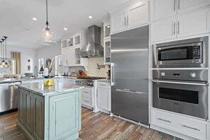 Uma cozinha moderna com eletrodomésticos de aço inoxidável, armários brancos e uma ilha central com limões.