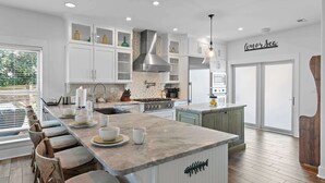 A modern kitchen with white cabinets, a large island, and a stainless steel range hood.